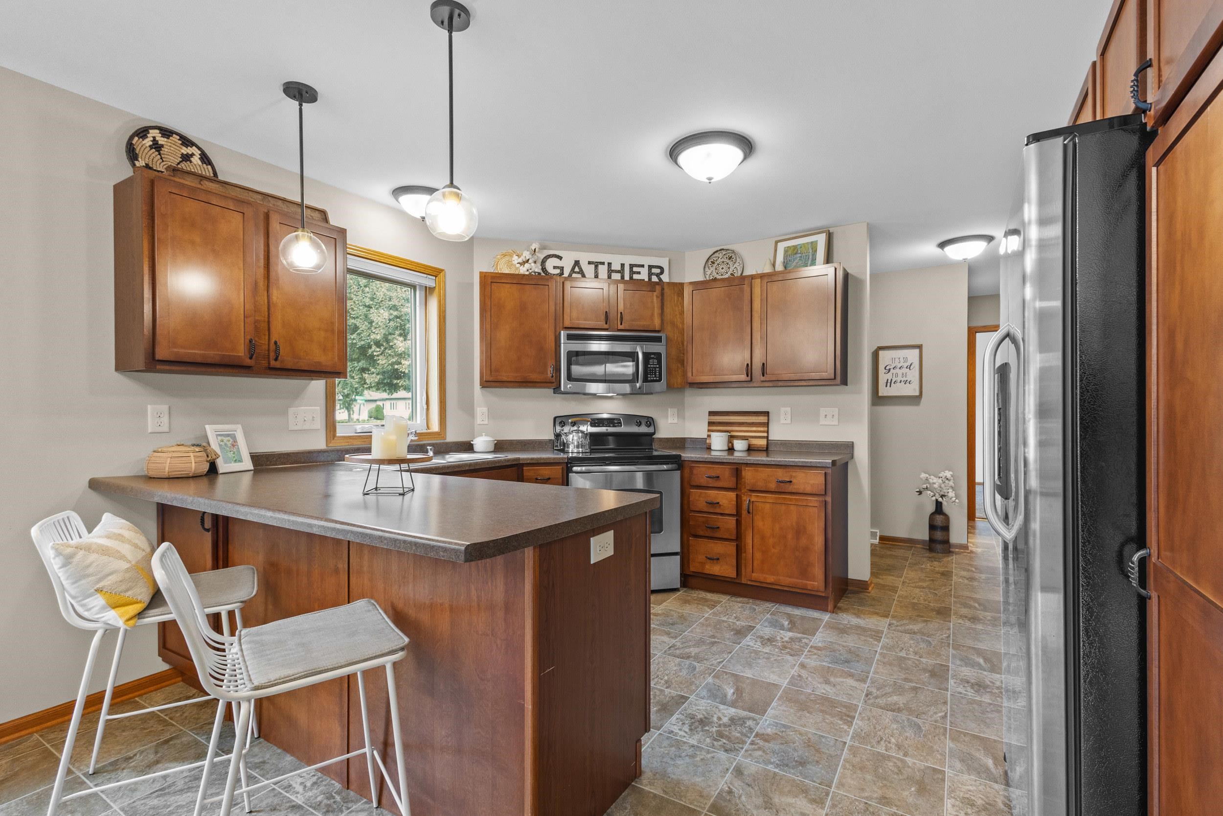 Kitchen with wood cabinetry, stainless steel appliances, and a large peninsula with seating.