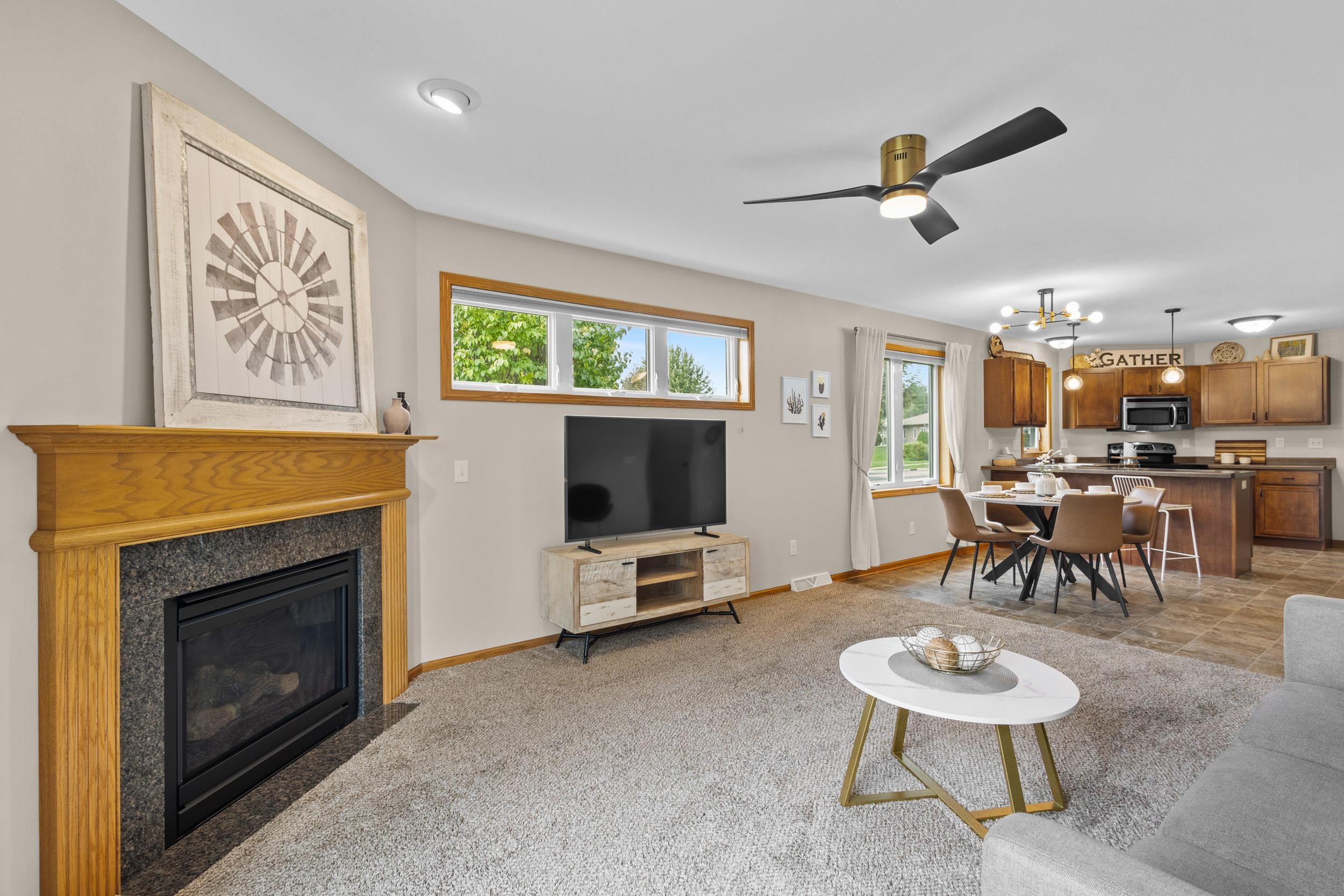 Open-plan living room and kitchen with a wood-trimmed fireplace and dining area.
