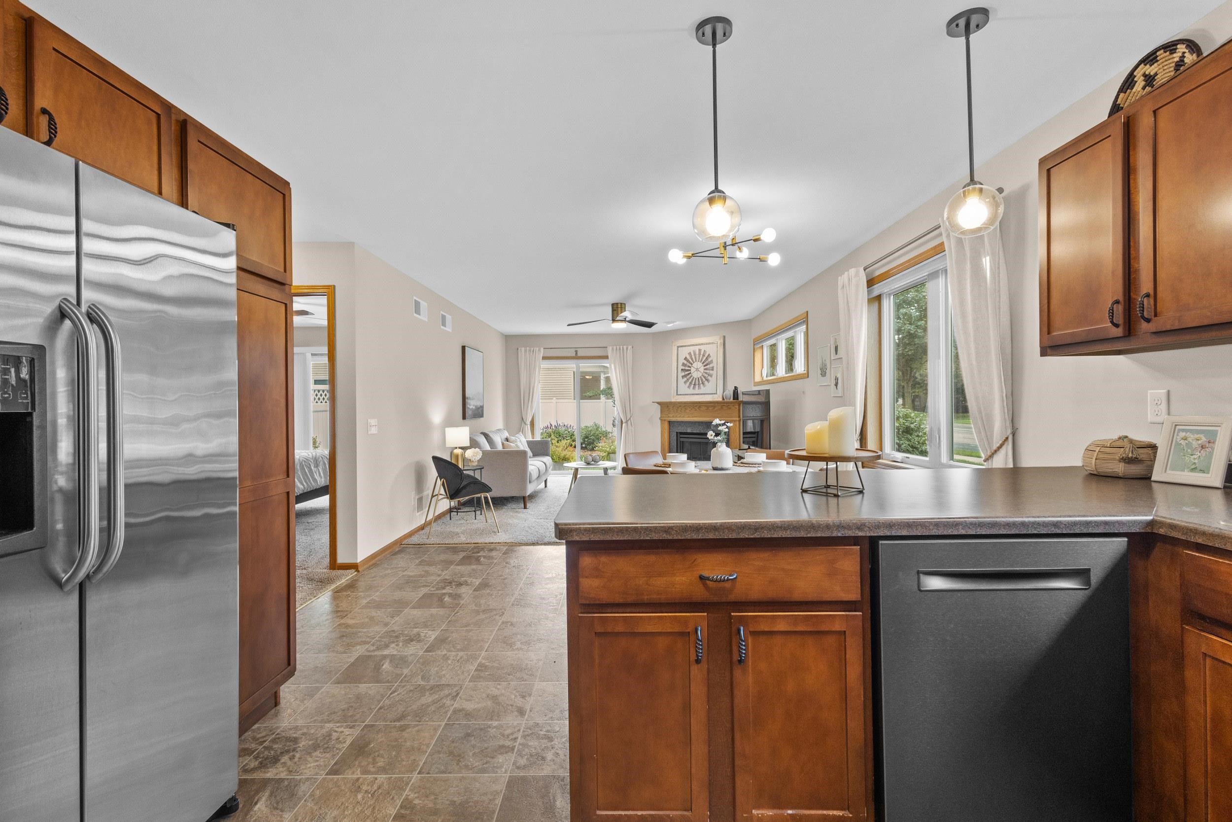 Kitchen with a wood-cabinet island and stainless appliances opens to a bright living room with a fireplace.
