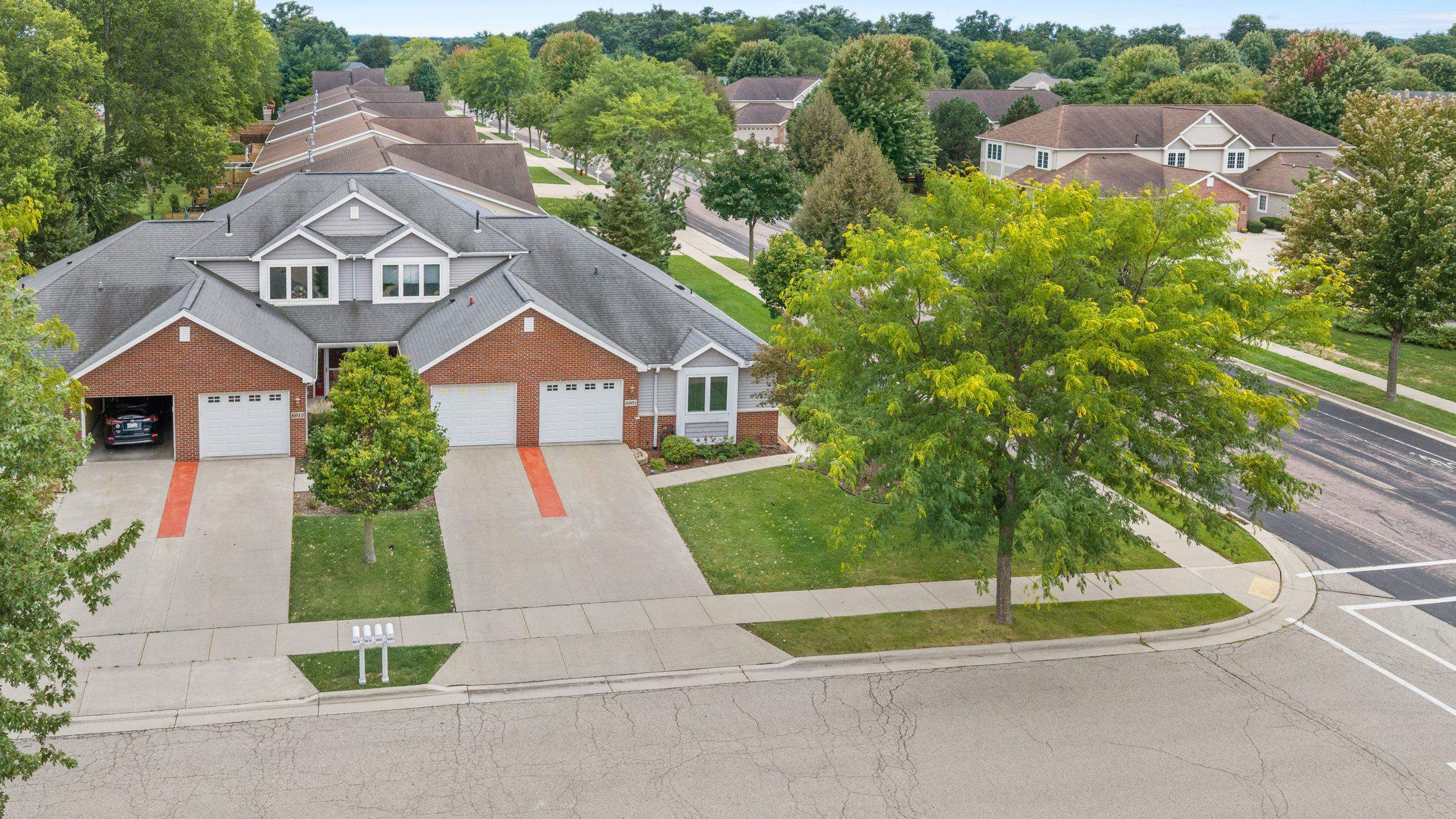 Aerial view of 6001 Osborn Drive, a brick-and-gray-sided home with an attached garage and tree-lined frontage.