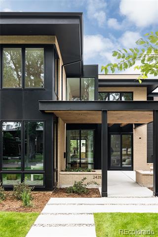 Modern two-story home with dark siding, light brick, and a covered front entry.