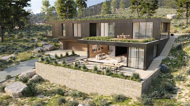 Modern glass-and-wood home on a rocky hillside, with a broad stone terrace and outdoor seating.
