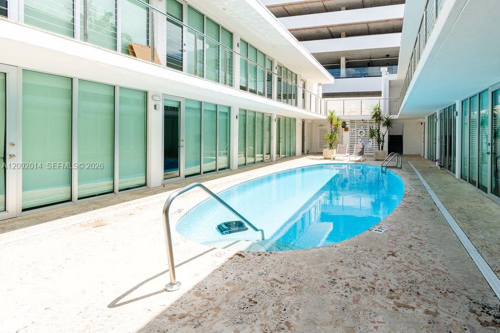 Condominium courtyard pool bordered by glass doors and pale stone paving.