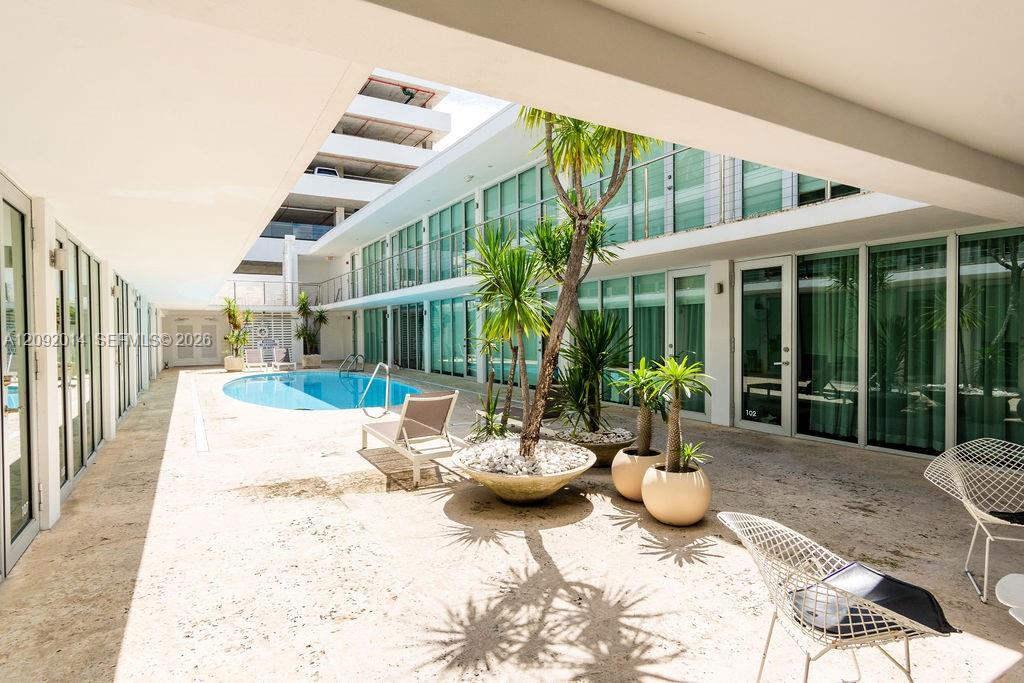 Condominium courtyard with a small pool, tropical planters, and wire lounge chairs.