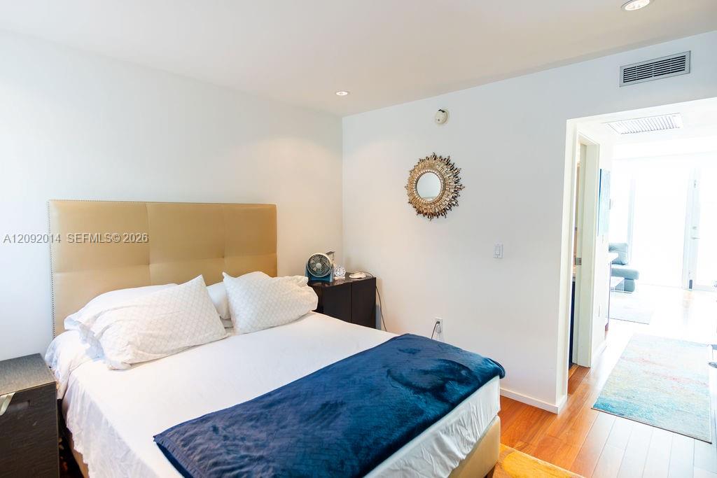 Furnished bedroom with a tan headboard, white bedding, and a dark blue throw.
