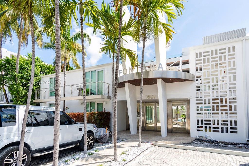 Fontana condominium entrance with a white facade, palm trees, and a geometric screen.