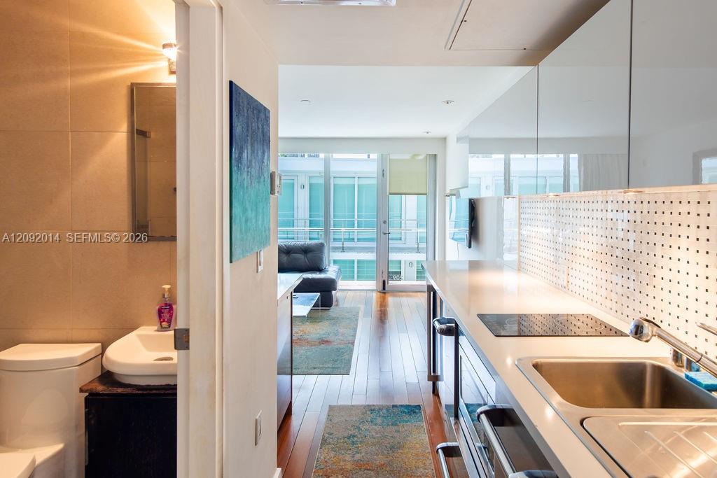 Modern condo kitchen with a perforated backsplash, opening onto a furnished living area and glass balcony doors.