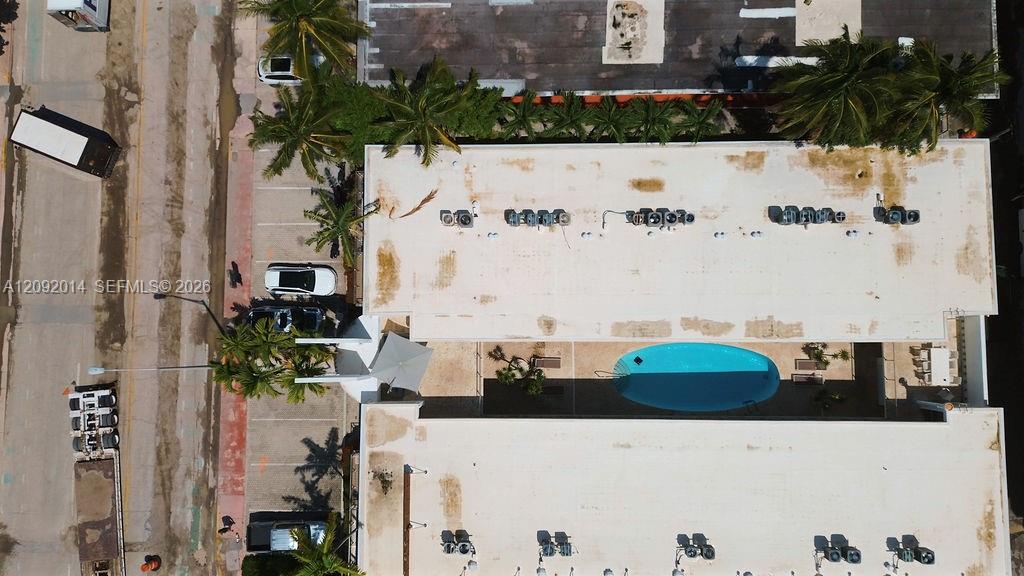 Aerial view of a condominium with a turquoise courtyard pool and palm trees.