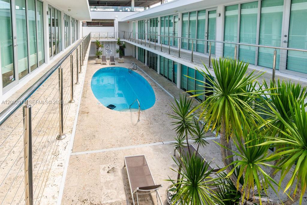 Condominium courtyard pool with glass-railed walkways and tropical landscaping.