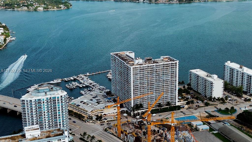 Waterfront high-rises beside a marina, with boats, a bridge, and construction cranes.