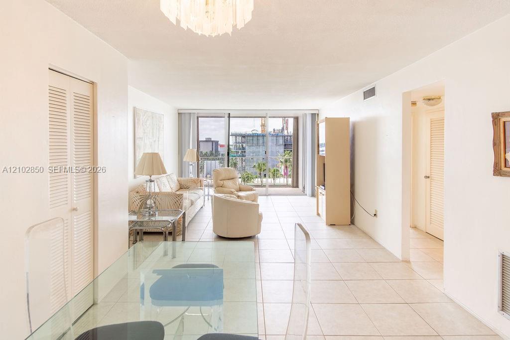 Bright condo living room with cream seating, white tile floors, and sliding doors to a balcony.