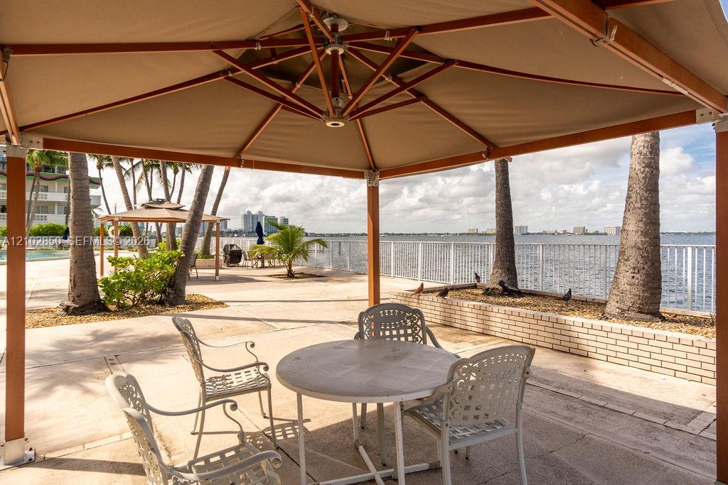 Waterfront patio with a shaded dining area, palm trees, and bay views.