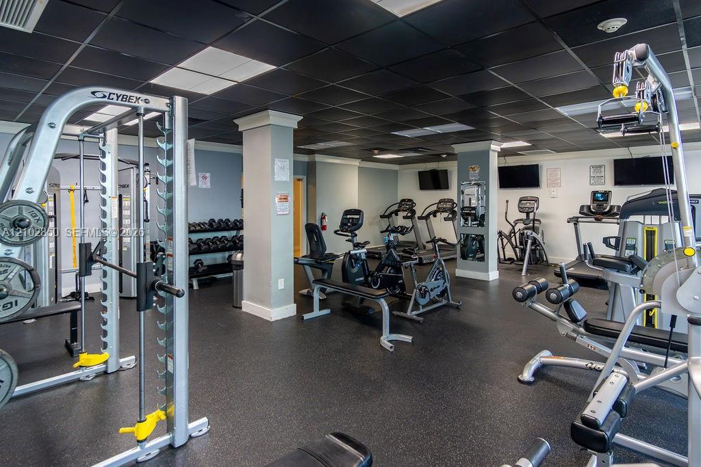Fitness room with weight machines, dumbbells, stationary bikes, elliptical trainers, and treadmills.