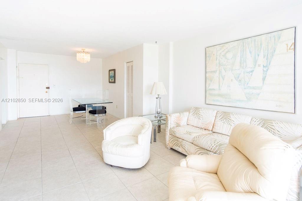 Furnished living room with white seating, large abstract artwork, and a glass dining table.