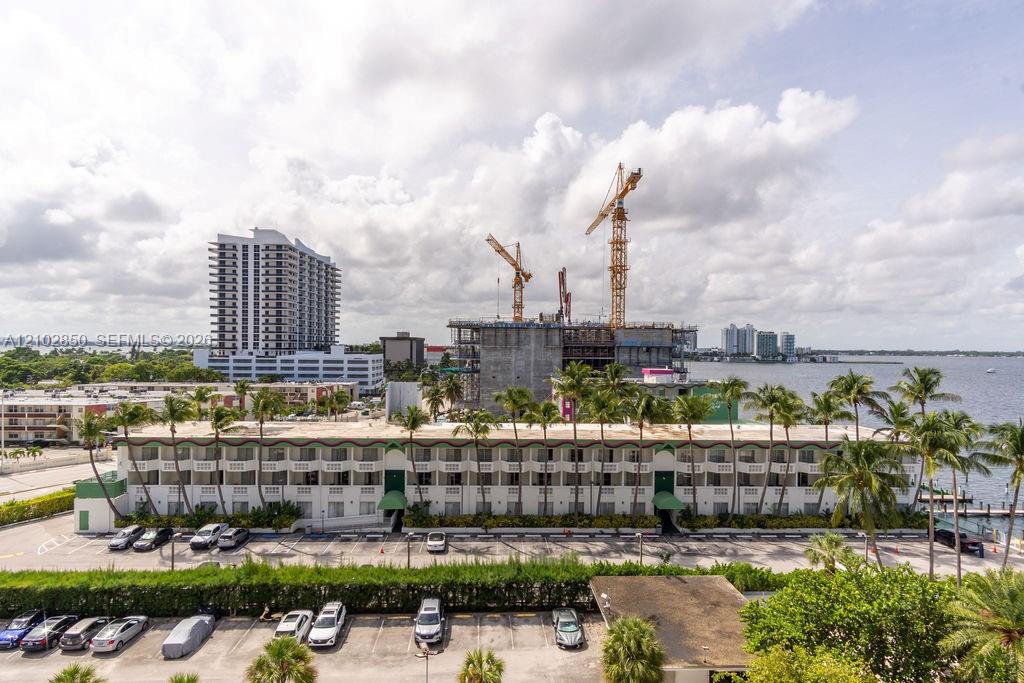 Waterfront view with palm trees, neighboring buildings, and construction cranes.