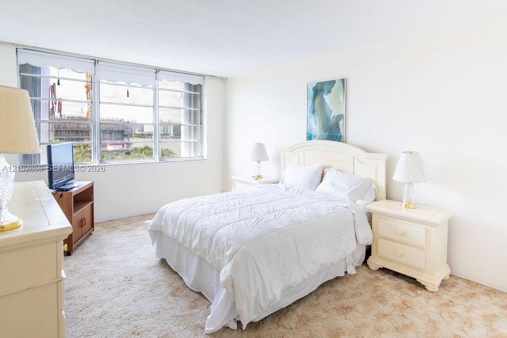 Bright bedroom with a white bed and large windows overlooking the water.