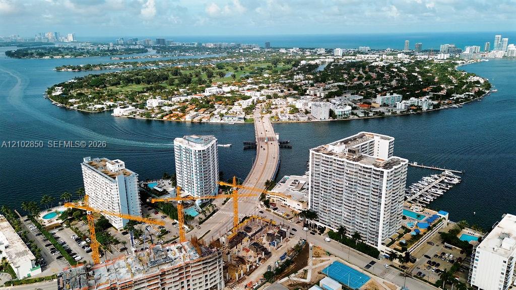 Aerial view of North Bay Village across the bay, with the causeway, waterfront buildings, and construction cranes.