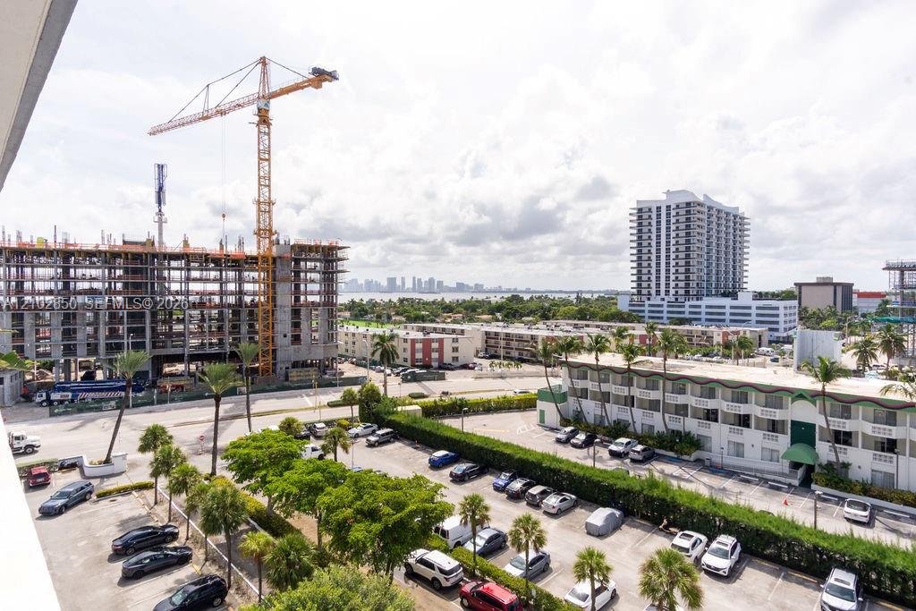 Elevated view over North Bay Village parking lots and buildings, with a tower crane and distant skyline.