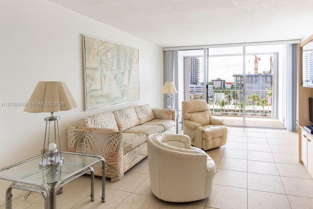 Living room with a patterned sofa, cream recliners, and sliding glass doors to a balcony.