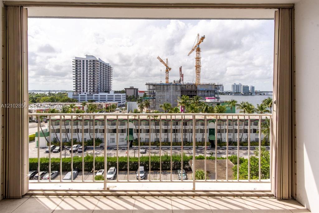 Condo balcony overlooking the bay, with construction cranes and high-rise buildings in the distance.
