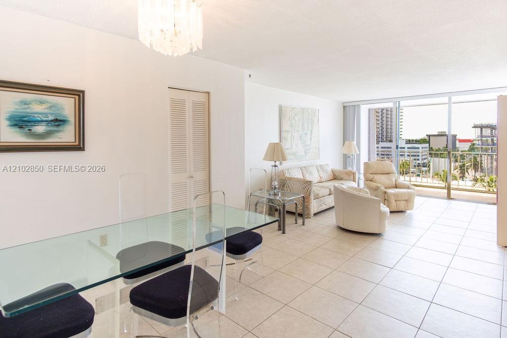 Living and dining area with a glass table, cream seating, and sliding doors to a balcony.