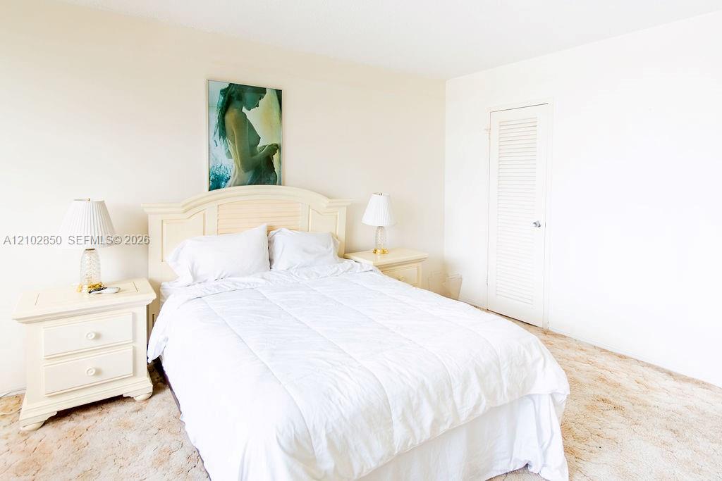 Bedroom with a white bed, matching cream nightstands, and framed artwork above the headboard.