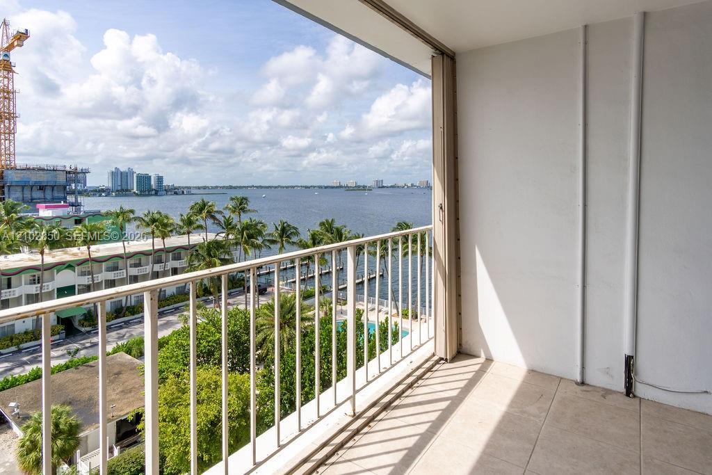 Empty tiled balcony overlooking a bay, marina docks, and distant buildings.