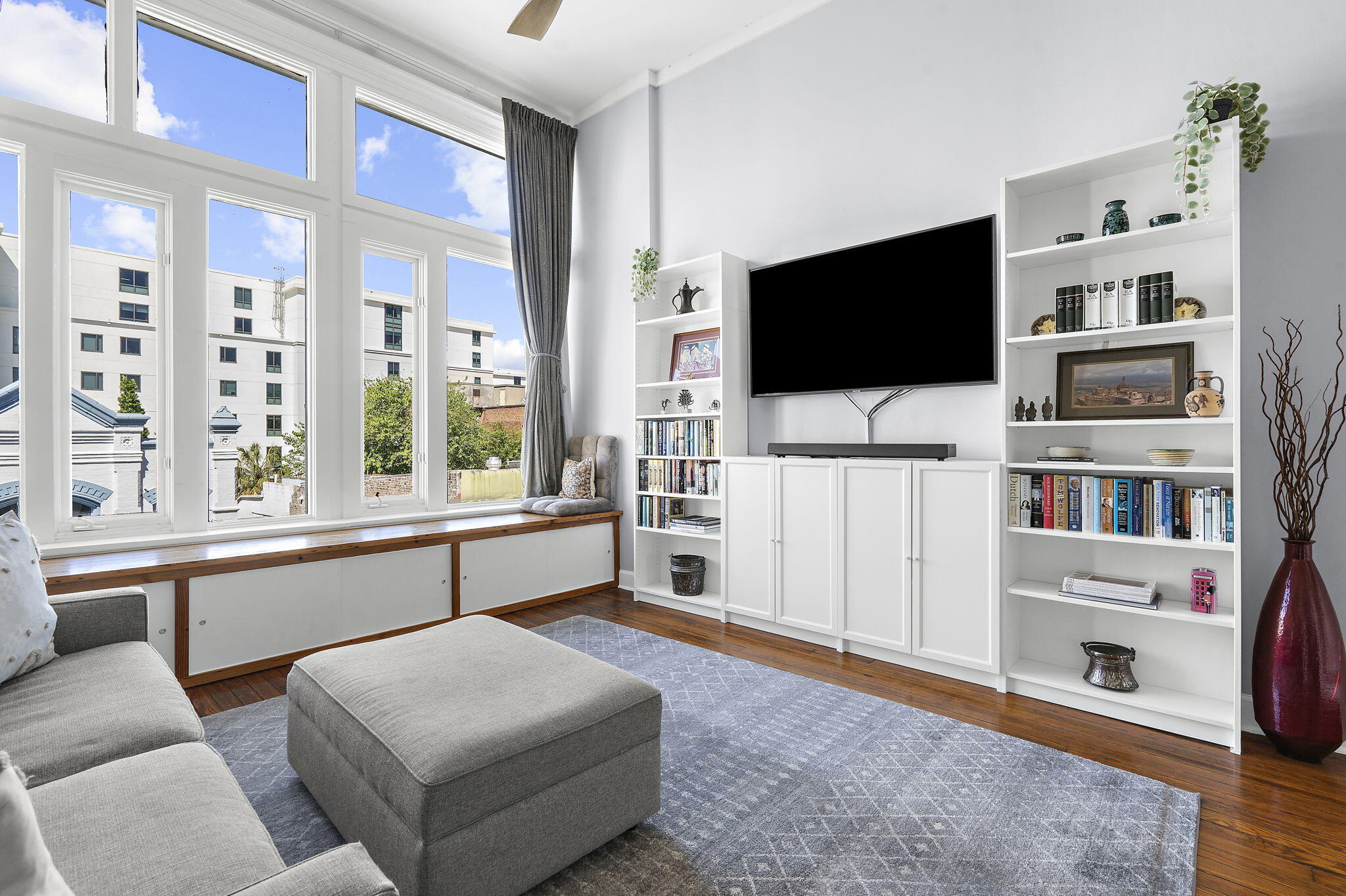 Living room with soaring windows, built-in bookcases, and a gray sectional sofa.