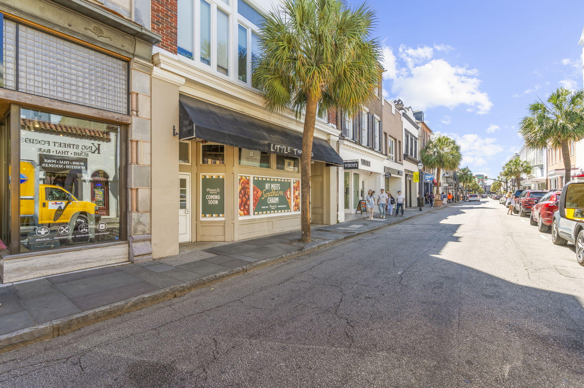 King Street in Charleston lined with storefronts and palm trees beneath a bright blue sky.