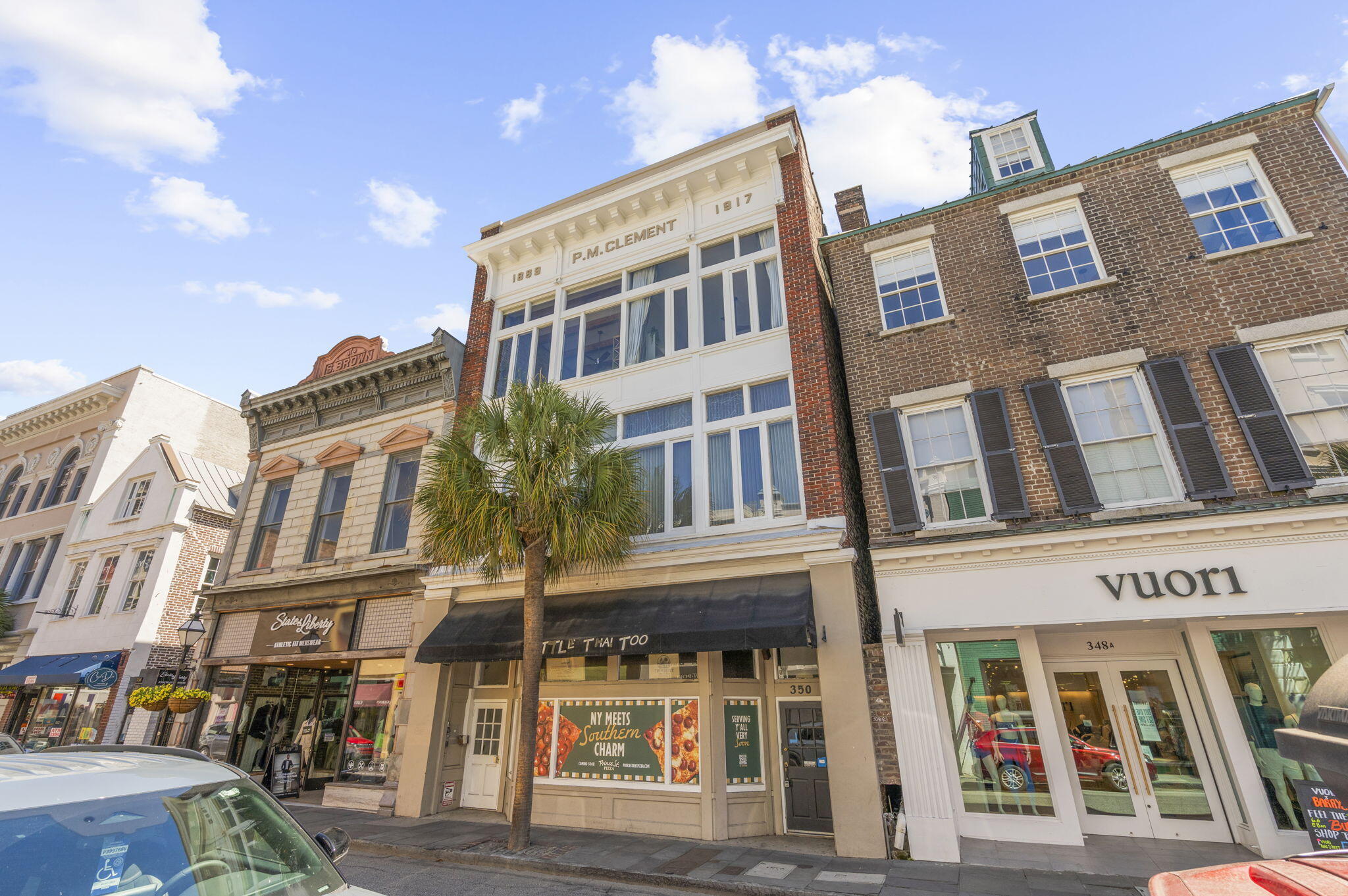 Historic King Street building with a white P.M. Clement facade, storefront awnings, and a palm tree.