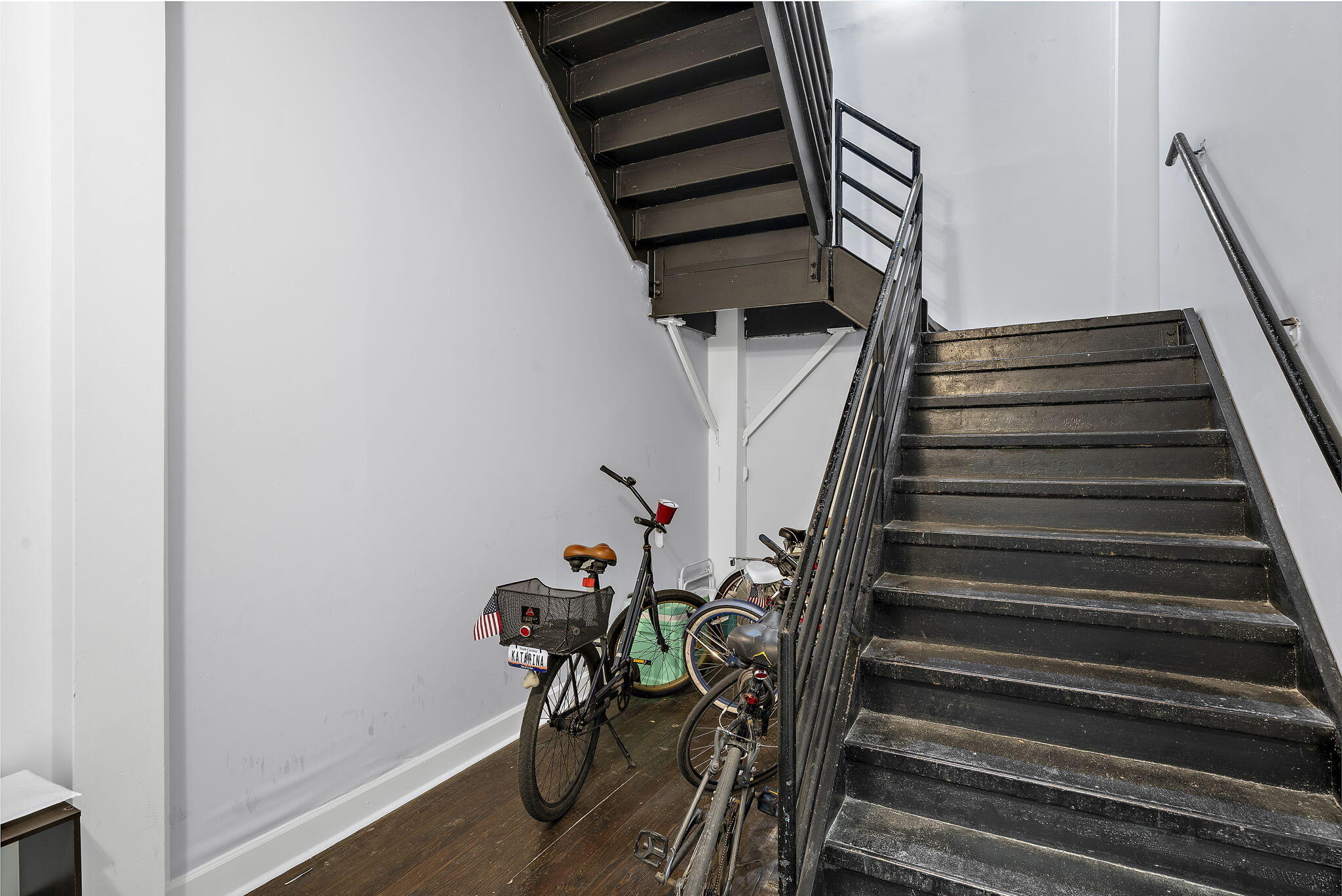 Common stairwell with dark wooden stairs and bicycles parked beneath them.