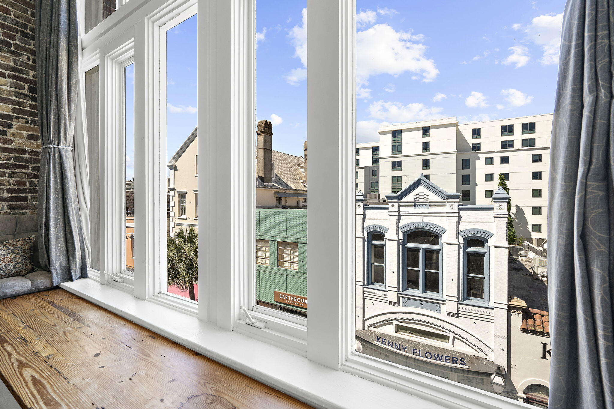Apartment windows overlook historic storefronts and modern buildings across the street.