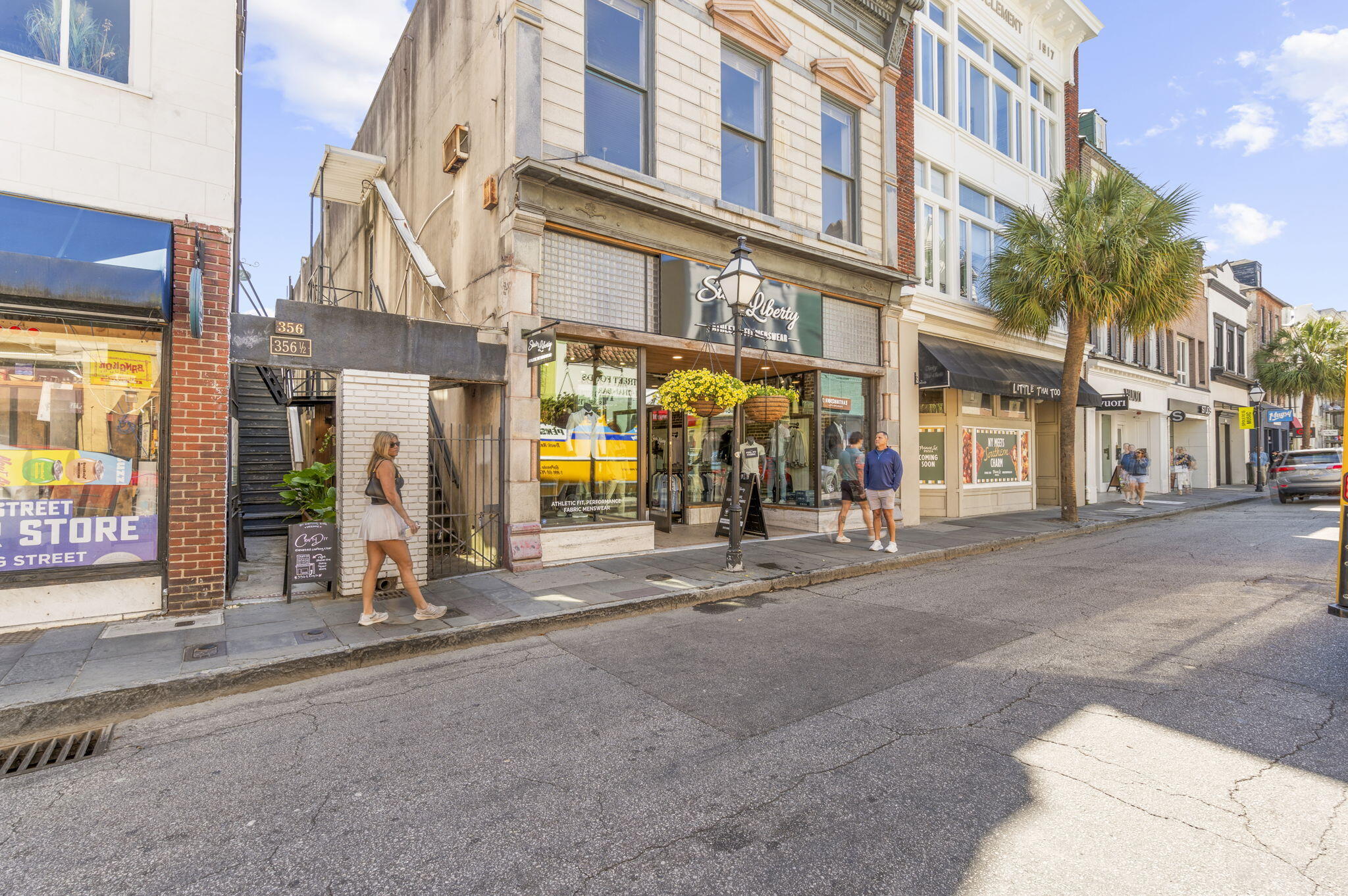 King Street storefronts with upper-floor windows, a palm tree, and pedestrians on the sidewalk.