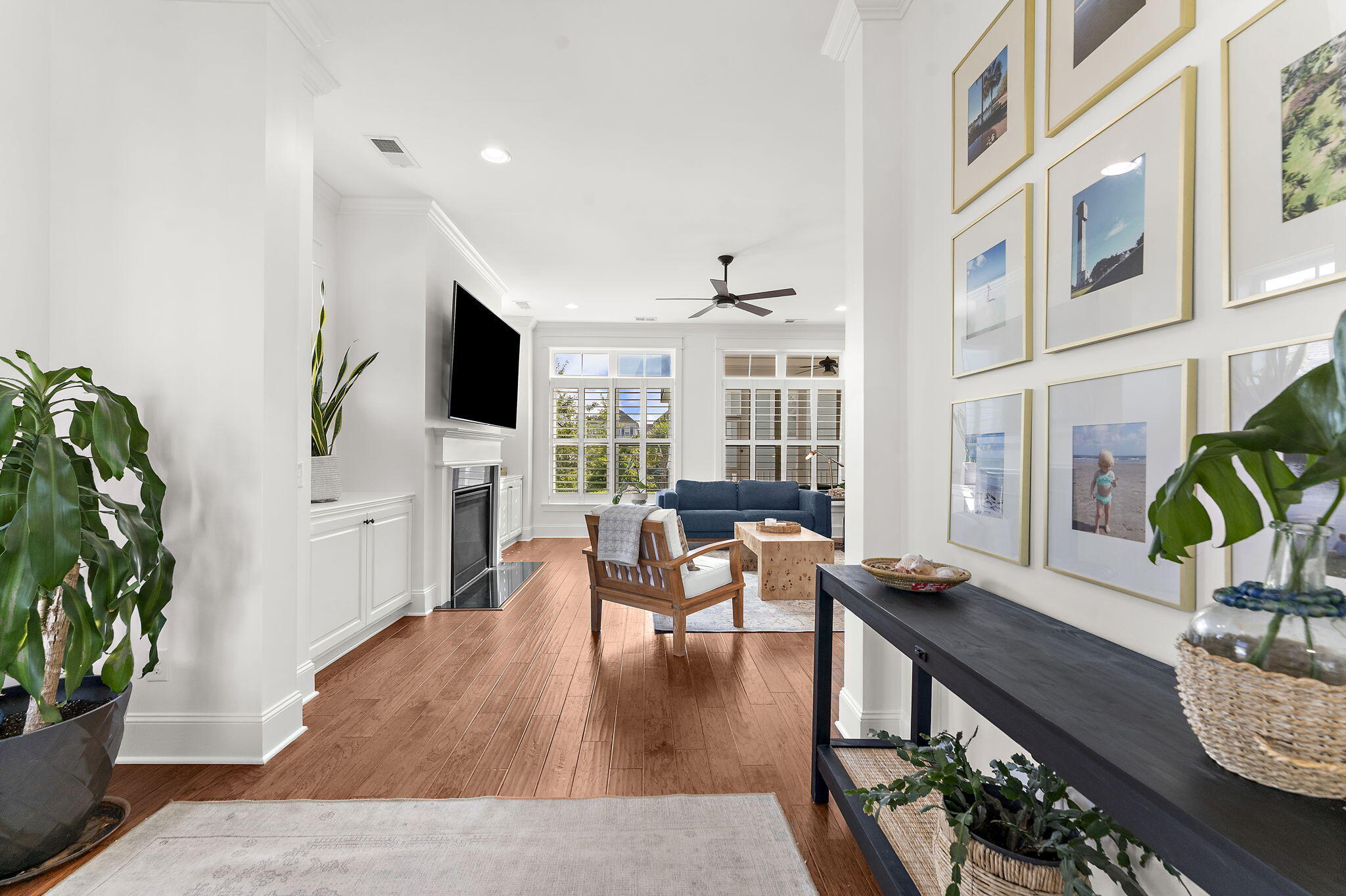 Furnished living room with a blue sofa, fireplace, hardwood floors, and framed photos on the wall.
