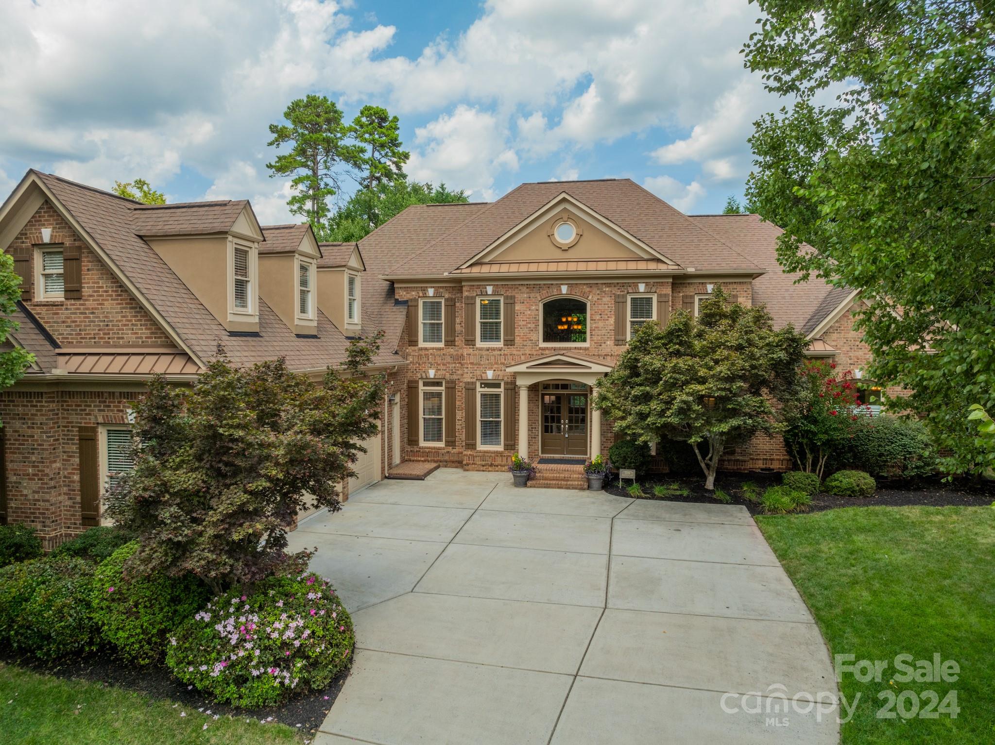 Two-story brick house with a circular gable window, wide driveway, and landscaped front yard.