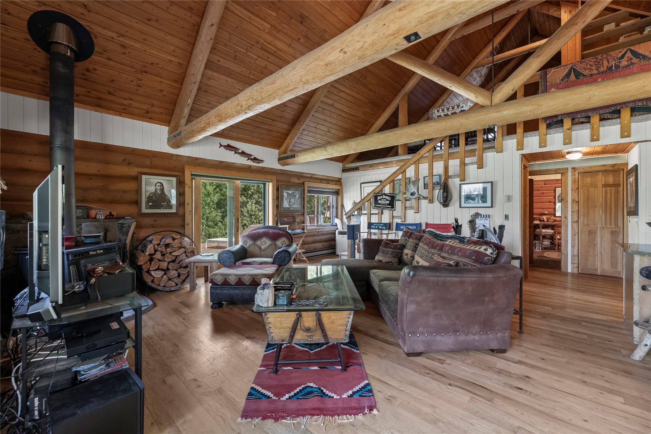Living room with vaulted timber ceiling, exposed beams, wood stove, and sectional sofa.