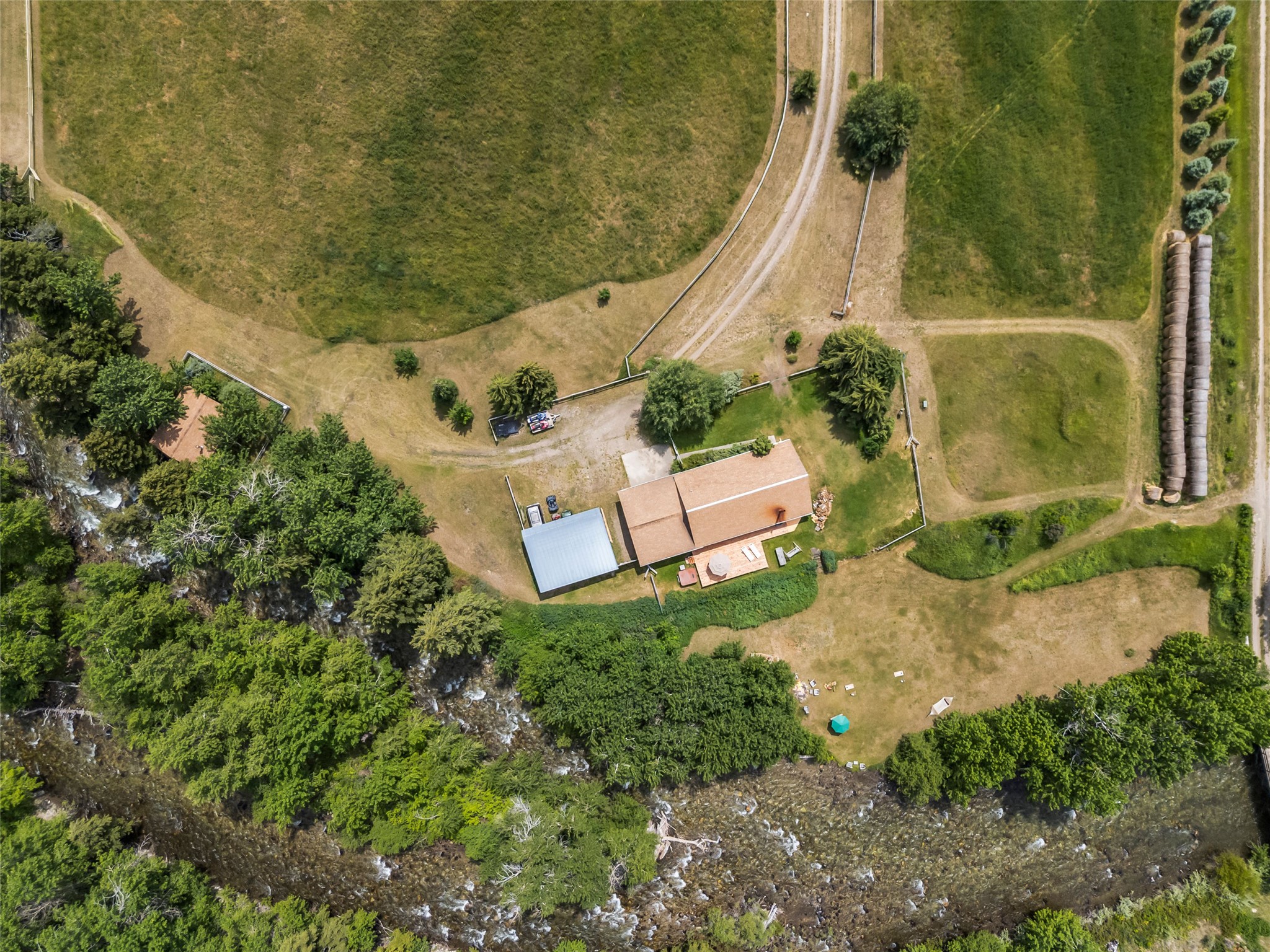 Aerial view of a home and acreage beside a tree-lined creek.