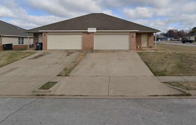 Single-story brick home with two garage doors and a wide concrete driveway.