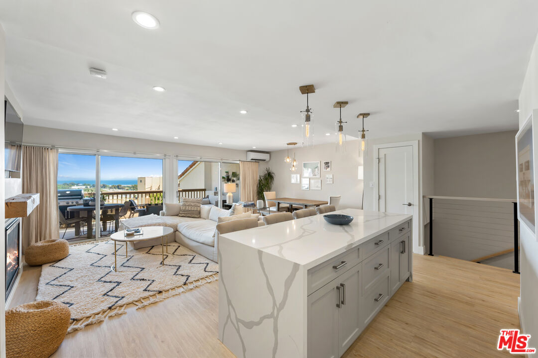 Open-plan kitchen and living area with a large island, sliding glass doors, and ocean views.