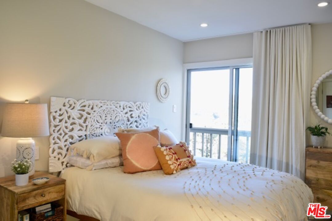 Bedroom with an ornate white headboard, coral accent pillows, and a sliding glass door.
