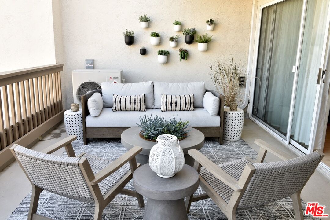 Covered patio with a cushioned sofa, woven chairs, and wall-mounted planters.