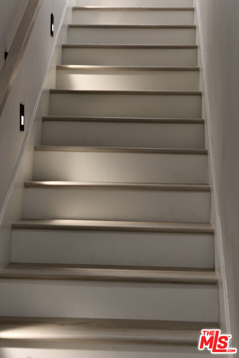 Interior staircase with light wood treads, white risers, and wall lights.