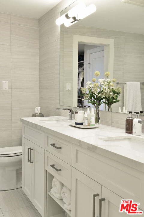 Bathroom with a white vanity, large mirror, and flowers on the counter.