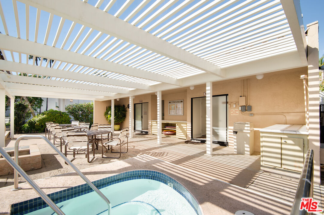 Shared pool courtyard with a small tiled pool, lounge chairs, and a white pergola.
