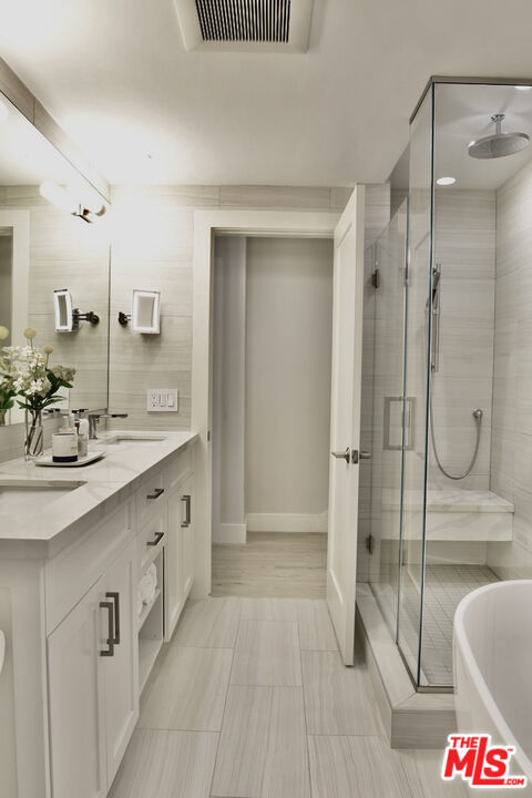 Bathroom with a glass-enclosed shower, freestanding tub, and long white vanity.