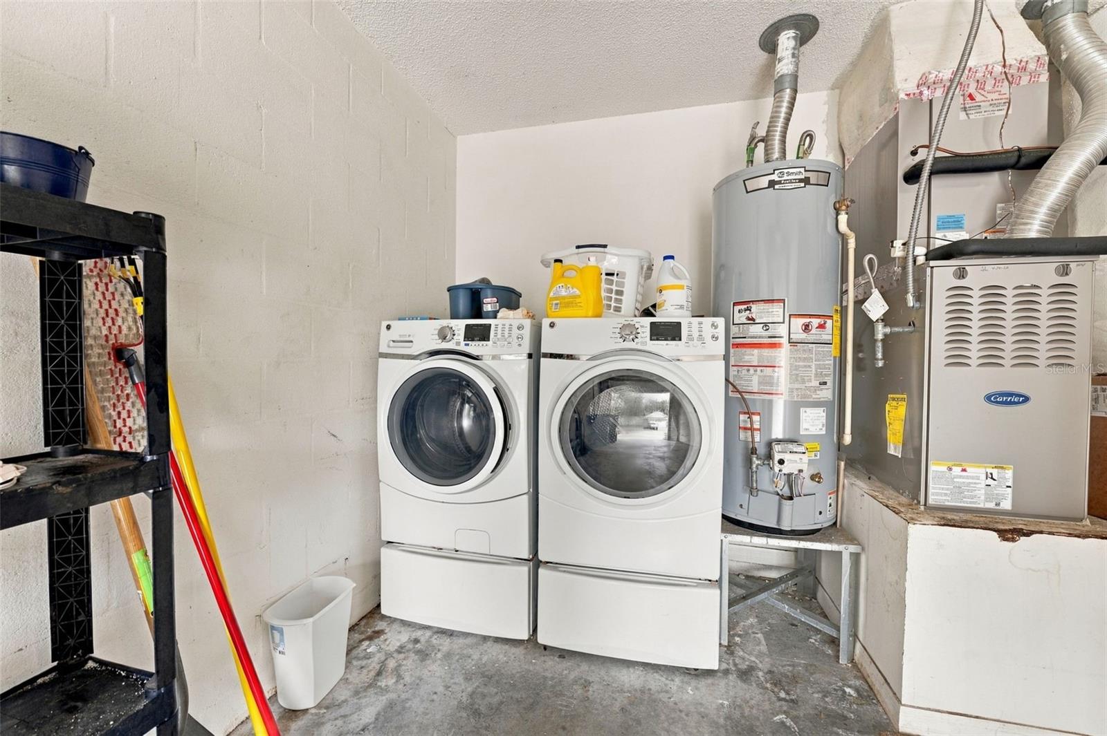 Laundry room with front-loading washer and dryer beside a water heater and furnace.