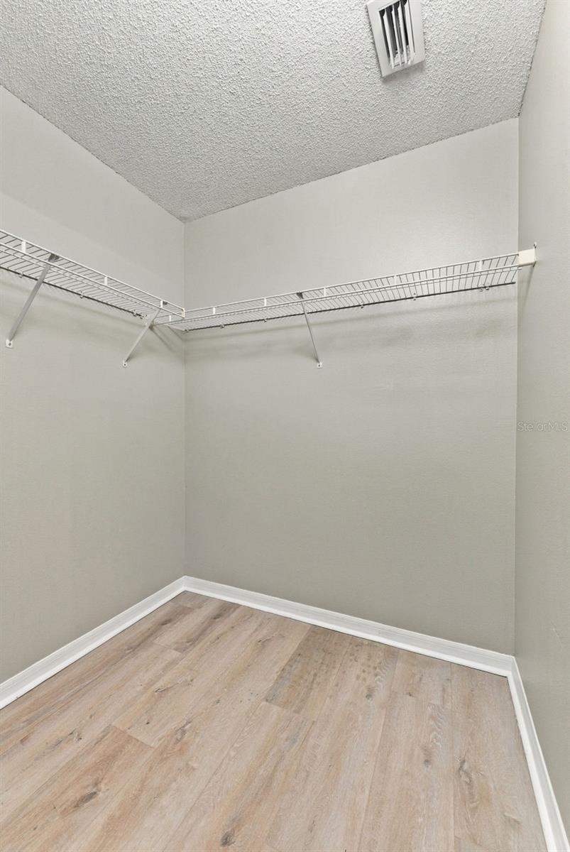 Walk-in closet with wire shelving on two walls and light wood-look flooring.
