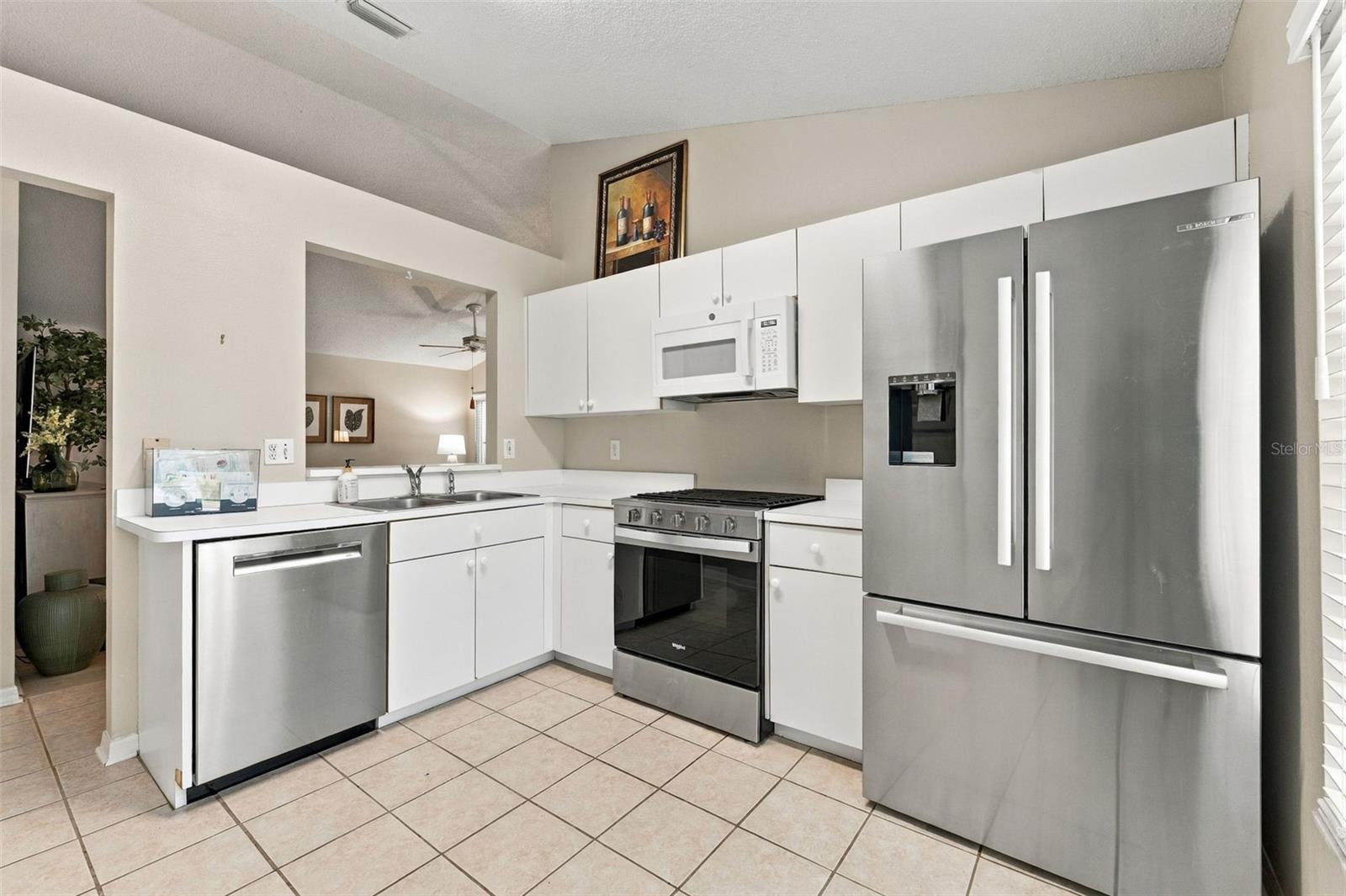 Kitchen with white cabinetry, stainless steel appliances, and tiled flooring.