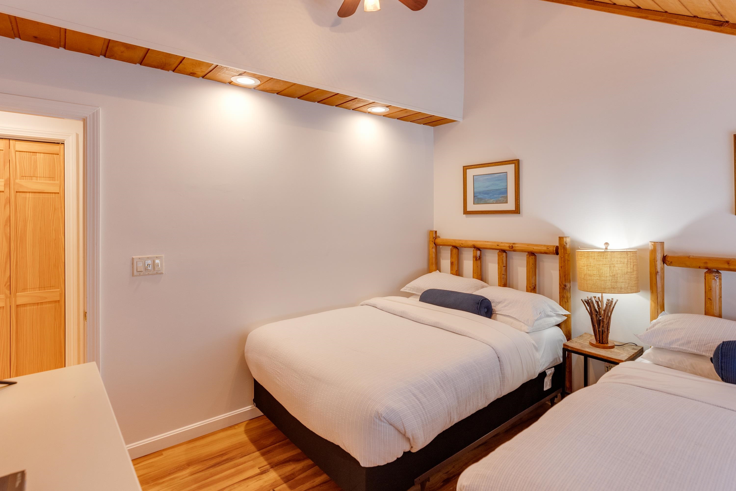 Bedroom with two beds, rustic wooden headboards, and exposed wood ceiling trim.