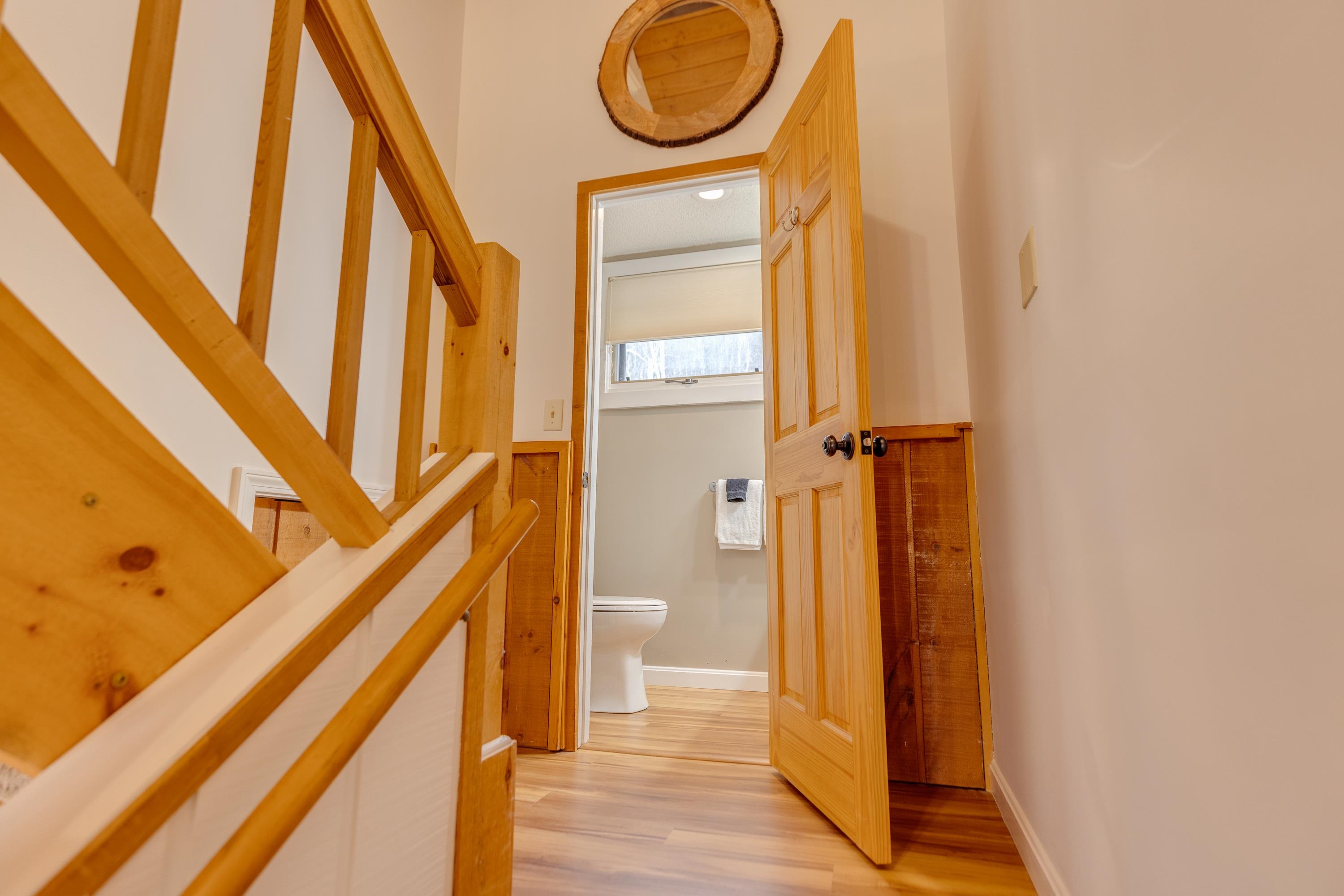 Hallway with a prominent wooden staircase railing and an open bathroom doorway.
